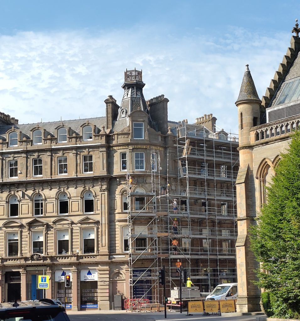 A stone corner building with scaffolding being removed