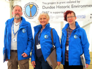 Three staff members wearing blue jackets with Dundee Historic Environment Trust logos