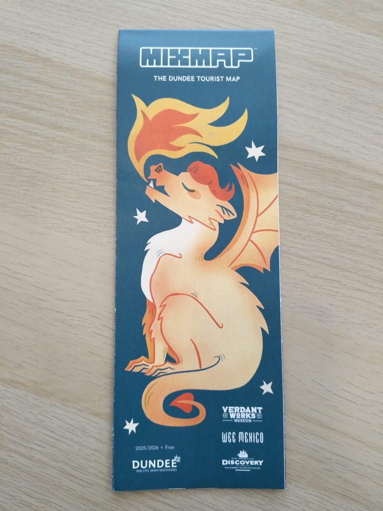 A physical edition of Mixmap, The Dundee Tourist Map. The cover shows a furry orange dragon with flame emitting from its mouth on a blue-green background.