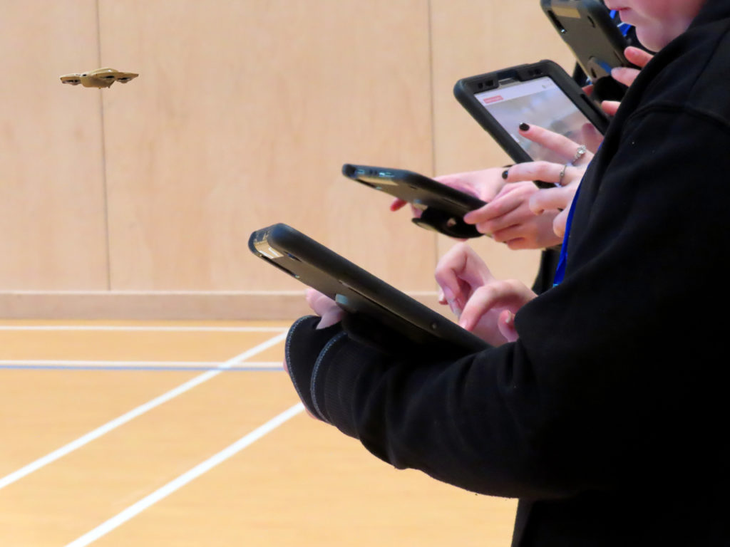A drone flies in front of several people holding tablets