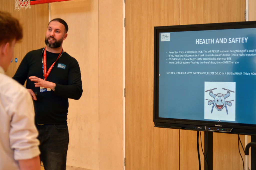 A person delivers a health & safety briefing for drones in front of a screen